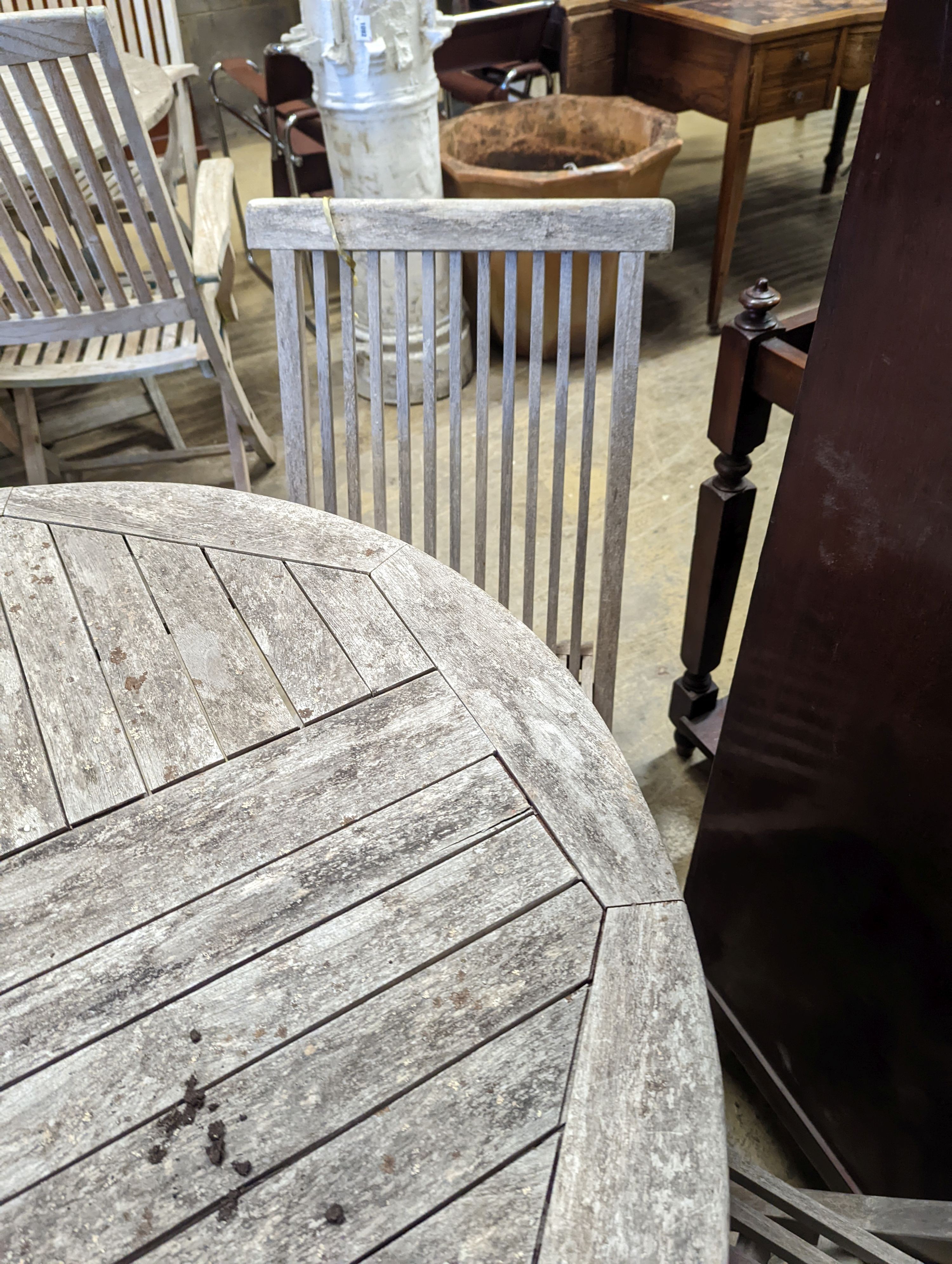 A circular weathered teak garden table, diameter 100cm, height 75cm together with four folding chairs